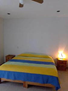 uma cama amarela e azul num quarto com um candeeiro em El Amate em Tepoztlán