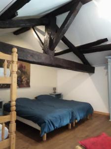 a bedroom with a blue bed in a room with beams at Gites les Lignons in Champniers