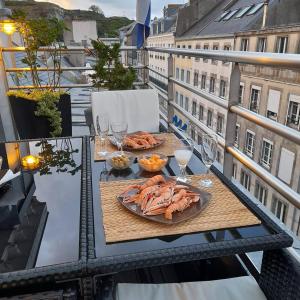 una mesa con 2 platos de comida en el balcón en Le Duplex avec Terrasse - Annonce d'un particulier en Granville