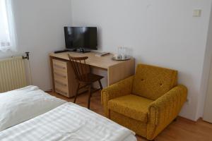 a bedroom with a desk with a chair and a television at Granny's in Svätý Jur