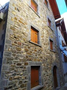 ein altes Steingebäude mit Holztüren und Fenstern in der Unterkunft APARTAMENTO Txapatera EN IZABA-ISABA in Isaba