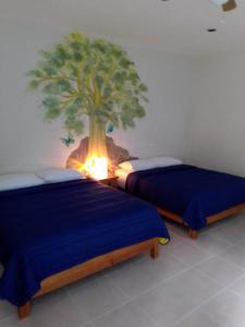 duas camas num quarto com uma árvore na parede em El Amate em Tepoztlán