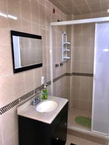ein Bad mit einem Waschbecken und einer Dusche mit einem Spiegel in der Unterkunft Casa el paraíso in Oaxtepec