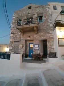 a stone building with a table and a balcony at Popi Studios in Astypalaia Town