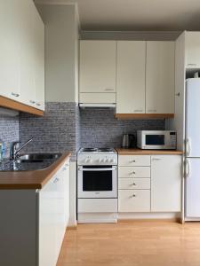 a kitchen with white cabinets and white appliances at Apartments ”Enkeli” in Kotka