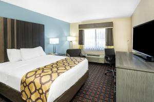 a hotel room with a bed and a flat screen tv at Baymont by Wyndham Tupelo in Tupelo