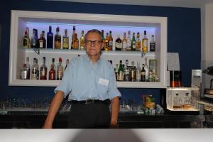 un hombre parado detrás de una barra con botellas de alcohol en Hotel Altis, en San Benedetto del Tronto