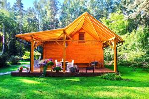 een houten hut met een terras in het gras bij Forest house with outdoor hot tub in Jūrmala