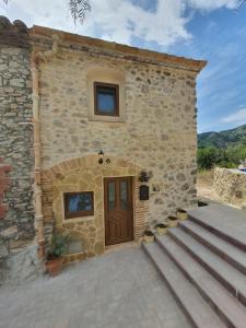 a stone building with a wooden door and stairs at La Ultima Casa Masboquera in Mas Boquera