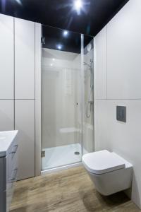 La salle de bains blanche est pourvue d'une douche et de toilettes. dans l'établissement ResiNest Apartamenty Butikowa Kamienica M40, à Białystok