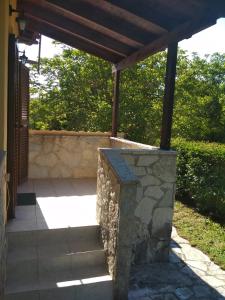 eine Terrasse mit einer Steinmauer und einem Holzdach in der Unterkunft Optasia in Karpenisi