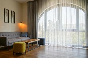 a living room with a couch and a large window at Apartique Hotel in Jerusalem