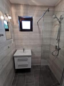 een badkamer met een douche, een wastafel en een glazen douche bij Na Fali in Dziwnów