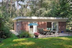 a small shed with a table and an umbrella at Drentse bungalow in natuur en rust in Spier