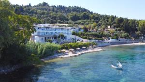 a boat in the water in front of a resort at Hotel Kaiser Bridge in Benitses