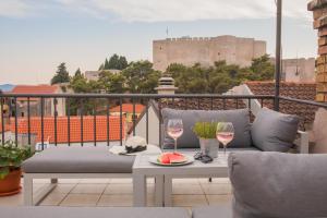 a balcony with a couch and two glasses of wine at Marijola apartments in Šibenik