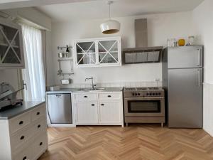 una cucina con armadi bianchi e frigorifero in acciaio inossidabile di casa Cervia by studio Ebi a Cervia