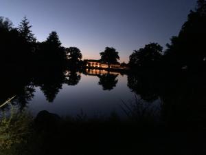ORANGERIE de CHATEL-Selection FIGARO & ELLE Magazine في Cleppé: اطلالة على بحيرة في الليل مع جسر