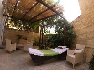 a patio with a bed and chairs and a pergola at The Maltese Sun in Sliema