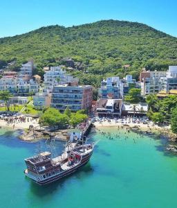 un barco en el agua junto a una playa en Hostel Toca da Moréia Bombinhas, en Bombinhas