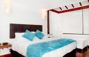 a bedroom with a large bed with blue pillows at Hotel Casona Usaquen in Bogotá