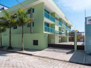 um edifício verde com duas palmeiras em frente em Apartamento com ar condicionado e Wi-fi, frente mar - 02 dormitórios - Edifício Luz do Sol em Ubatuba
