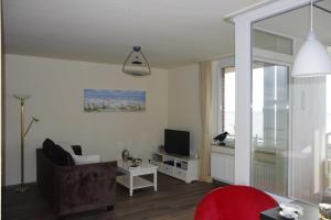 a living room with a couch and a television at 146 Suedstrand Meerblick in Wilhelmshaven