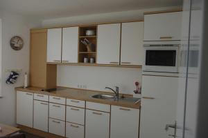 eine Küche mit weißen Schränken, einer Spüle und einem Kühlschrank in der Unterkunft 146 Südstrand Meerblick in Wilhelmshaven
