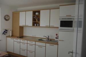 a kitchen with white cabinets and a sink and a refrigerator at 146 Suedstrand Meerblick in Wilhelmshaven