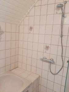 La salle de bains est pourvue de carrelage blanc, d'une douche et d'une baignoire. dans l'établissement Winsum - Groningen - 6 pers. Cosy Cottage - Op en Bie t Woater, à Winsum