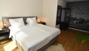 a bedroom with a large bed with white sheets at Hotel Brasserie de Kaai in Steenbergen