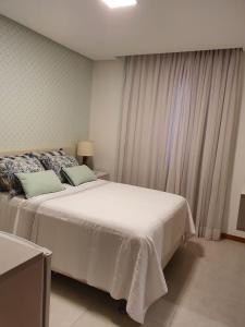 a bedroom with a white bed and a window at Itacimirim boulevard in Itacimirim
