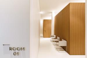 a row of white chairs in a hallway with a row of brown walls at Meo Design Suites & Spa in Catania