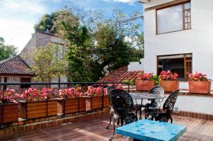 eine Terrasse mit einem Tisch, Stühlen und Blumen in der Unterkunft Hotel Casona Usaquen in Bogotá