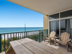 a balcony with a wooden table and chairs and the ocean at Jade East Condominiums in Destin