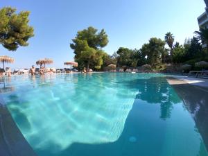 een groot zwembad met blauw water in een resort bij Hotel King Saron Club Marmara in Isthmia