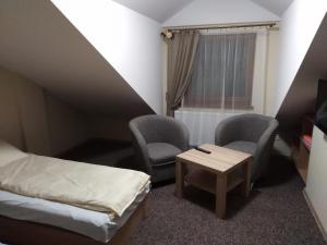 Cette chambre comprend un lit, deux chaises et une table. dans l'établissement Ośrodek Wczasowy "Wczasy pod gruszą", à Biecz