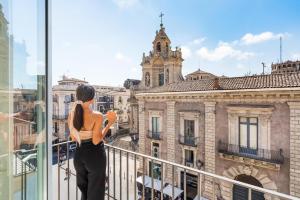 a woman taking a picture of a building from a balcony at Meo Design Suites & Spa in Catania
