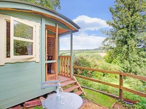 a green tiny house with a porch and a table at Hill view Holiday Home with Garden in Taunton