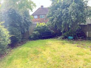 un patio con un árbol y un banco frente a una casa en The Harvest 2, en Canterbury