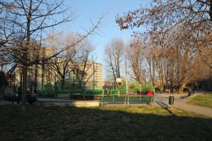 un banco de parque en un parque con un edificio al fondo en Milano: accogliente appartamento in zona comoda en Milán