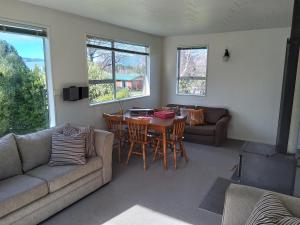 a living room with a couch and a table and chairs at The Willow - Hanmer Springs Holiday Home in Hanmer Springs