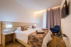 a hotel room with a bed and a blue chair at Casas Amarelas Azores in Ponta Delgada