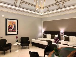Cette chambre d'hôtel comprend deux lits, une table et des chaises. dans l'établissement ETNEA STYLE CATANIA LUXURY ROOMS, à Catane