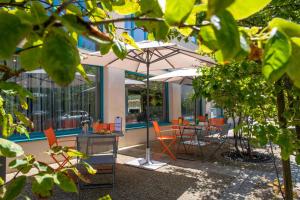 a patio area with tables, chairs and umbrellas at Best Western Premier Masqhotel in La Rochelle