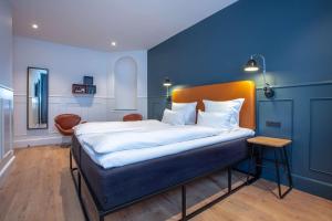 a bedroom with a bed with a blue wall at The Huxley Copenhagen, BW Premier Collection in Copenhagen