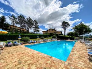 a swimming pool with chairs and a house in the background at Agriturismo Comparone Casavecchia in Città di Castello