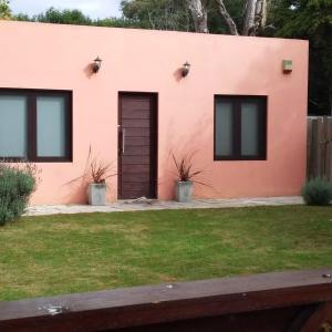 een roze huis met een deur en een tuin bij ROSALIMON in Nueva Palmira