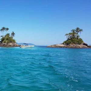 un barco en el agua al lado de una isla en Flat Angra Inn, Angra dos Reis, en Angra dos Reis