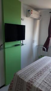 - une chambre dotée d'une télévision à écran plat sur un mur vert dans l'établissement Suites Vila de Iracema, à Fortaleza